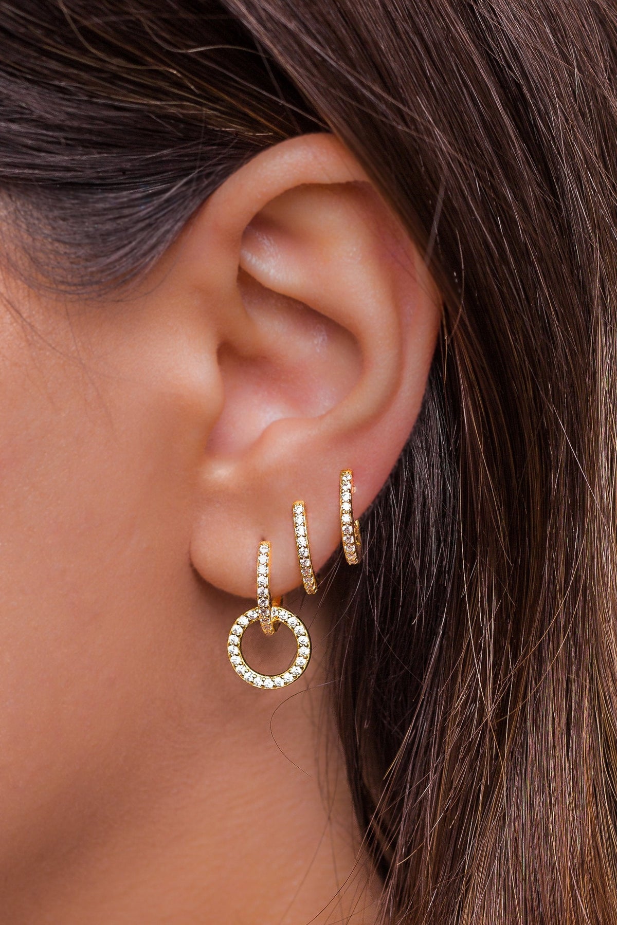 A woman's ear with several piercings, each set with a small sparkling earring