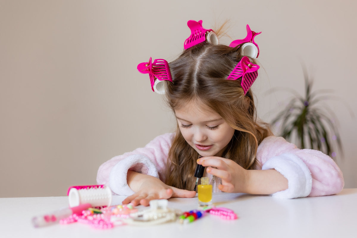 A little girl painting her nails at a table scattered with play make-up