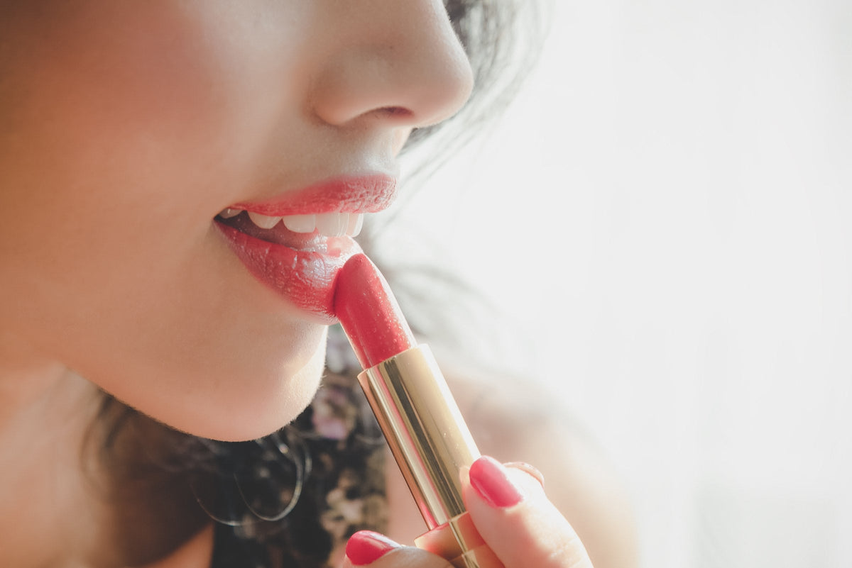 A woman tracing her lips with a lip liner pencil, close up