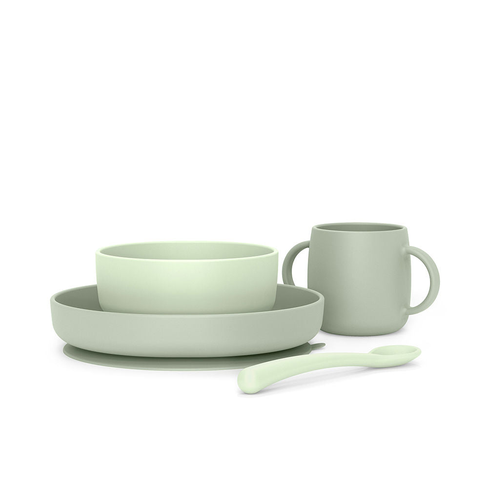 Soft silicone four-piece dinnerware set in light green and grey: bowl, divided plate, two-handled mug, spoon, matte finish — crafted with minimalist design for everyday use by Suavinex