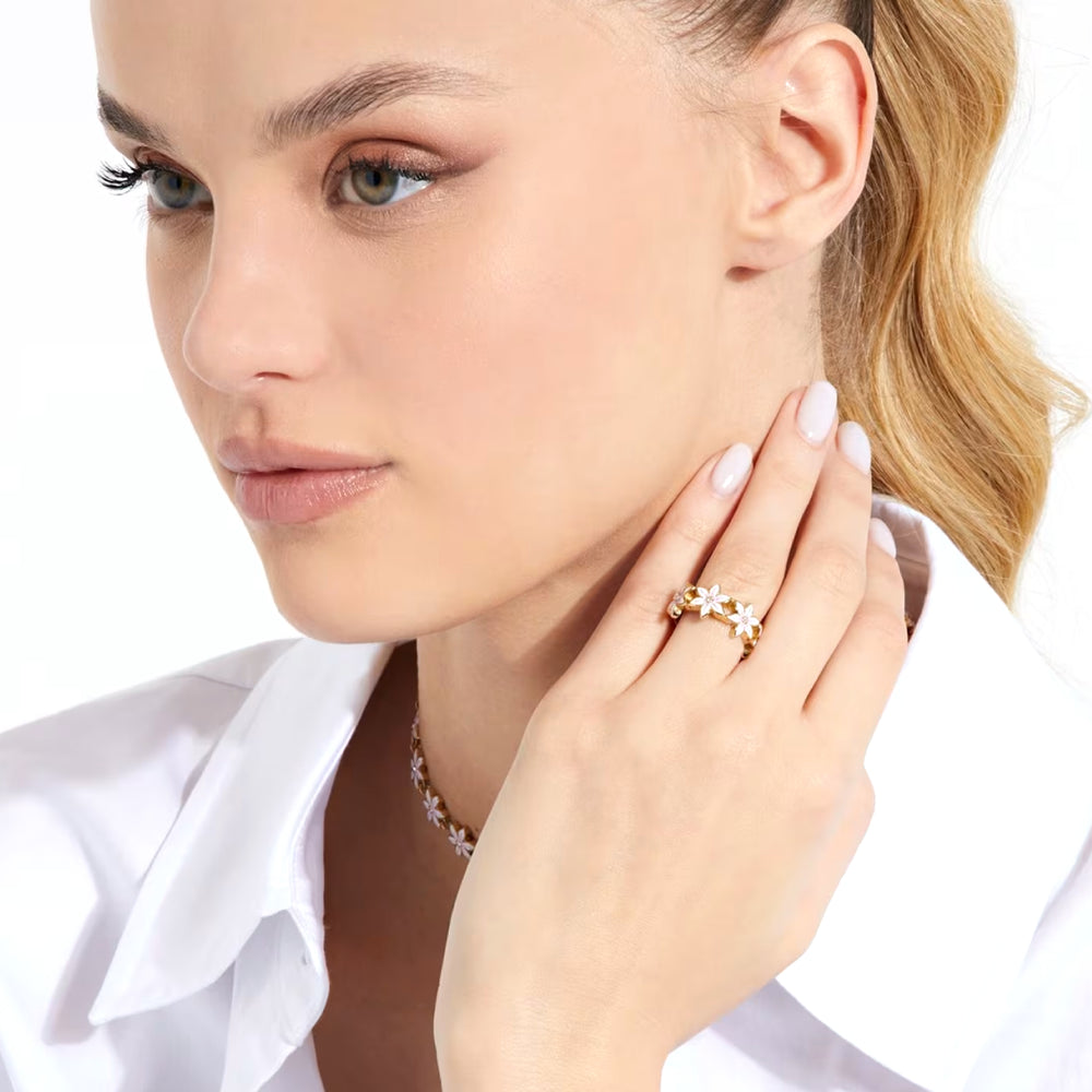 Gold floral ring with layered petals and a pink gemstone center on a slim band, polished and textured finishes