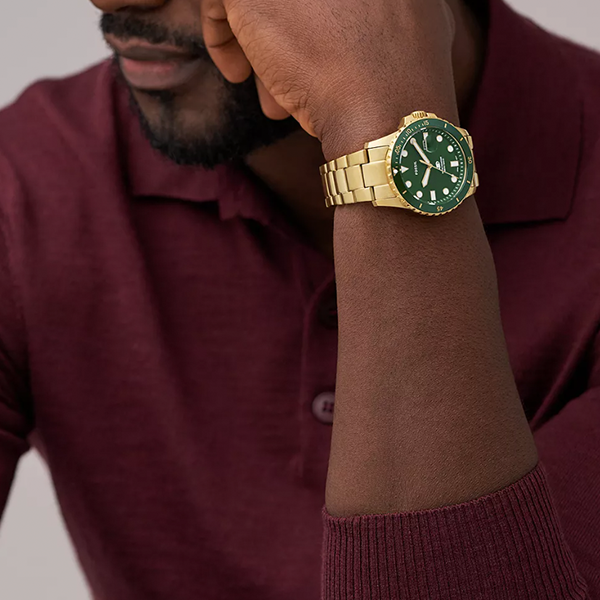 Gold-tone diver watch with green dial, rotating bezel, luminous markers, and metal bracelet